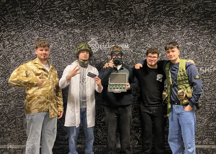 Smiling team holding props after escaping Contagion escape room at The Escape Room Guys in Derby