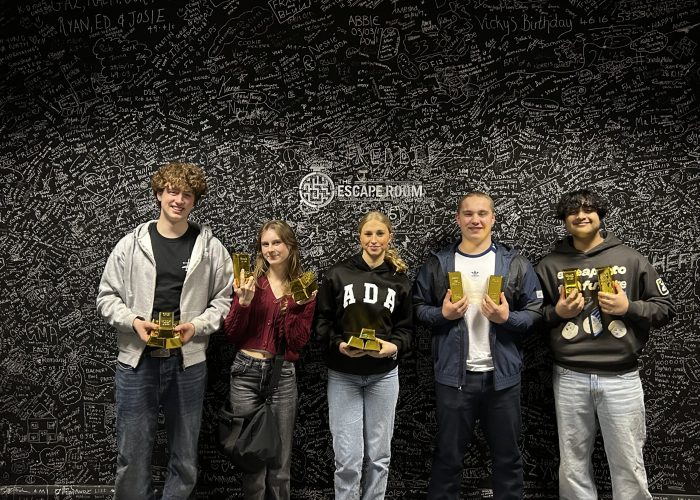 Escape room players posing with gold bars after completing The Grand Heist game at The Escape Room Guys in Derby